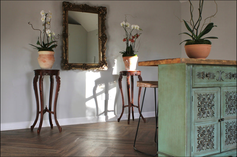 Decorative room with ornate mirror, potted plants, and a green cabinet.